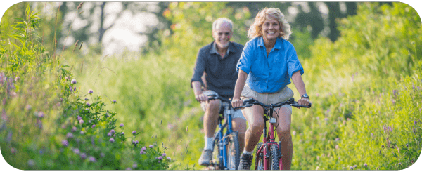 An older man and woman cycling together An older man and woman cycling together
